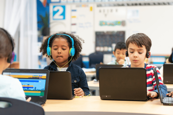 Pequenos estudantes com fones de ouvido fazem atividade em laptop